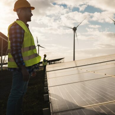 Man working for solar panels and wind turbines - Renewable energy concept - Focus on male worker face