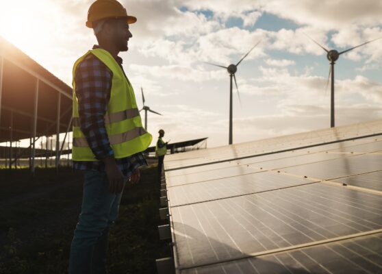 Man working for solar panels and wind turbines - Renewable energy concept - Focus on male worker face